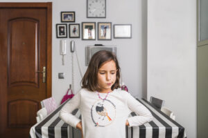Child standing alone at home while parents prepare safety expectations before leaving